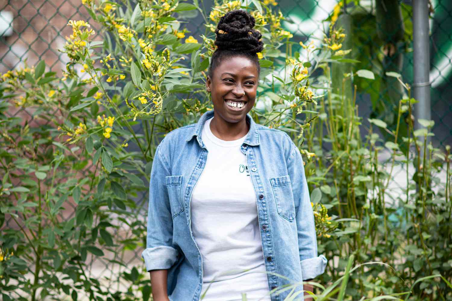 Yemi Amu standing in front of a bushel of flowers