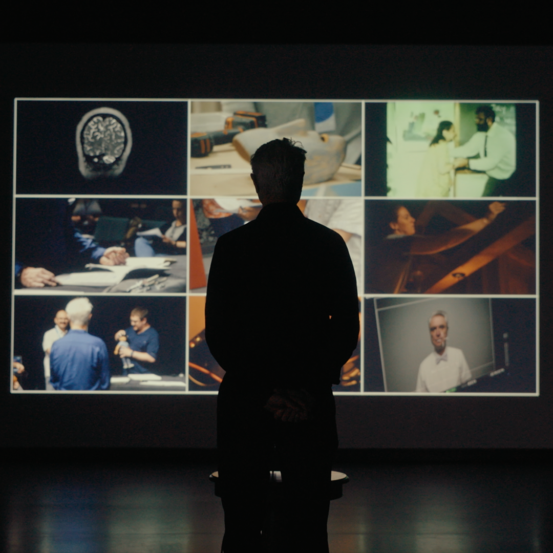 Man standing in front of a project screen of different videos