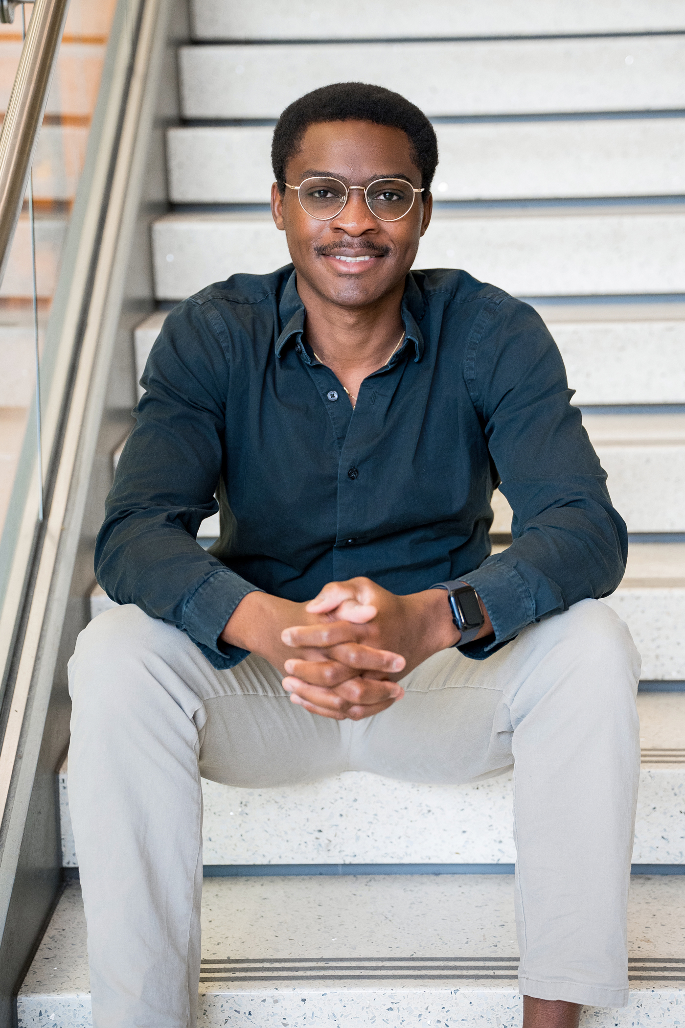 Photo of Dr. Alabi sitting on steps at the Electrical and Computer Engineering department University of Illinois Urbana-Champaign.