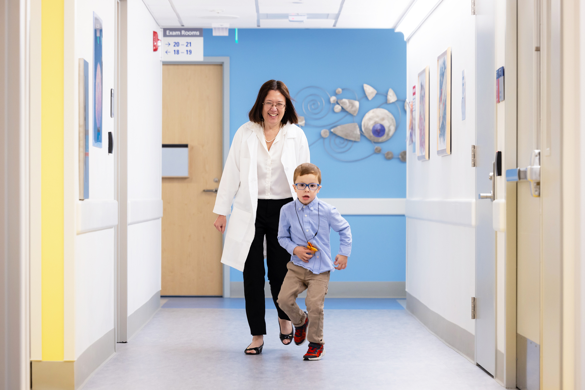 Wendy Chung with young Simons Searchlight participant in hospital corridor.