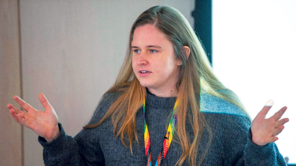 A woman speaking with her hands while wearing a University of Edinburgh lanyard.