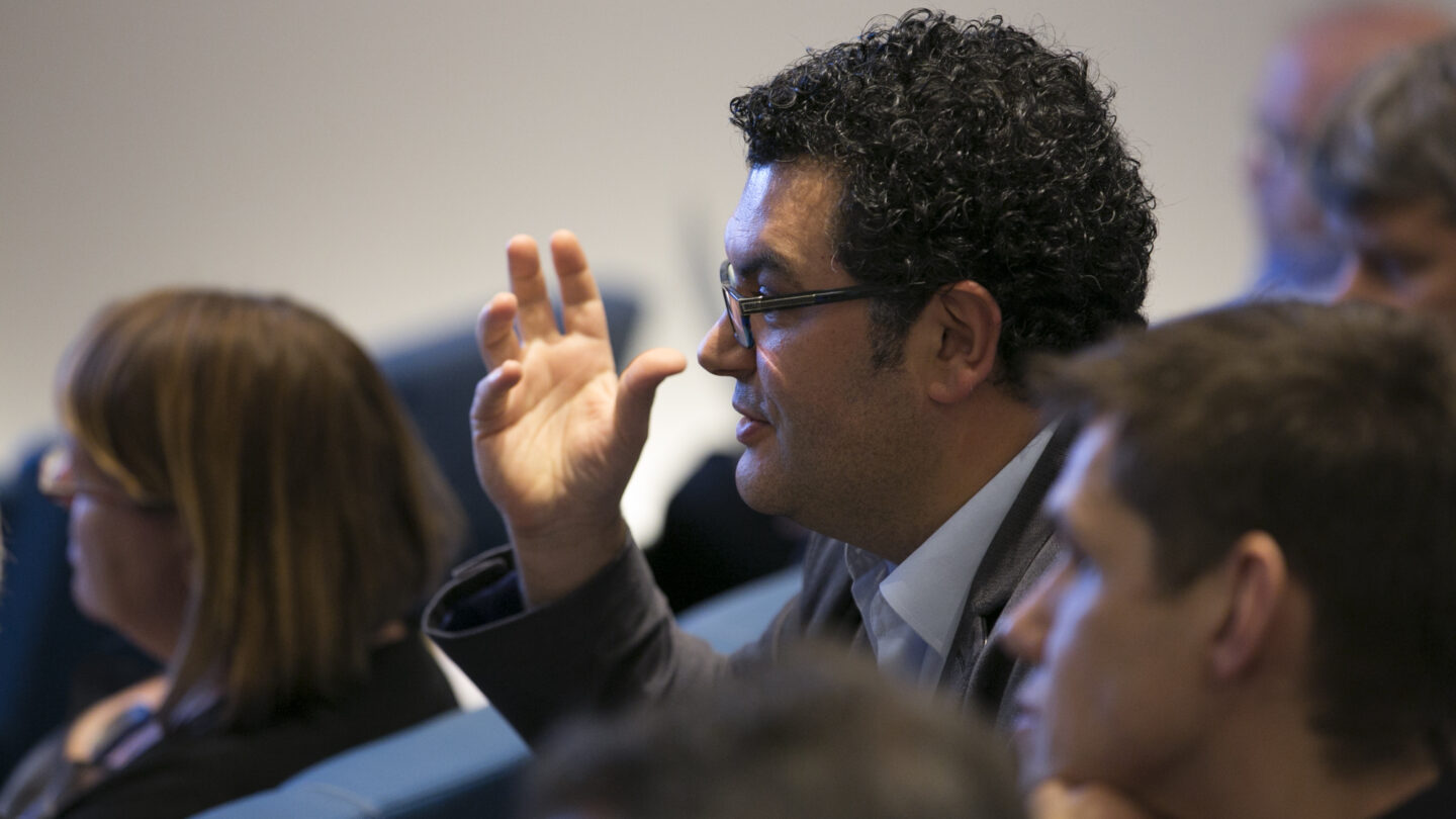 Man sitting and talking as he gesticulates with his hand