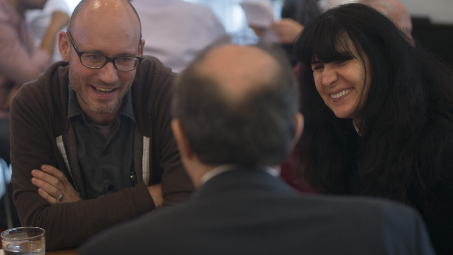 Three people sitting at a table and laughing