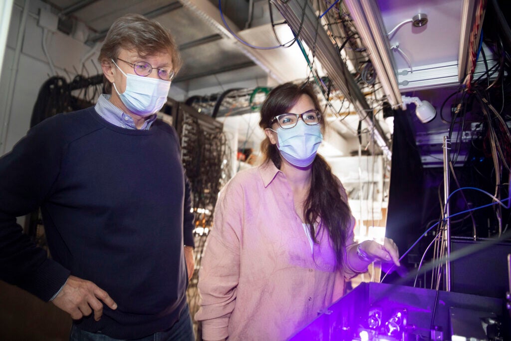 A photograph of Mikhail Lukin and lead researcher Giulia Semeghini in a room of wired servers.