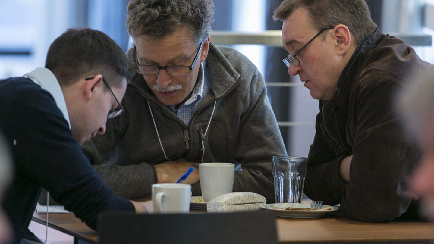 Three men sitting and collaborating at a table