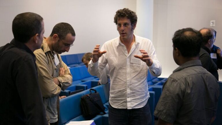 Five people standing in a lecture hall and talking