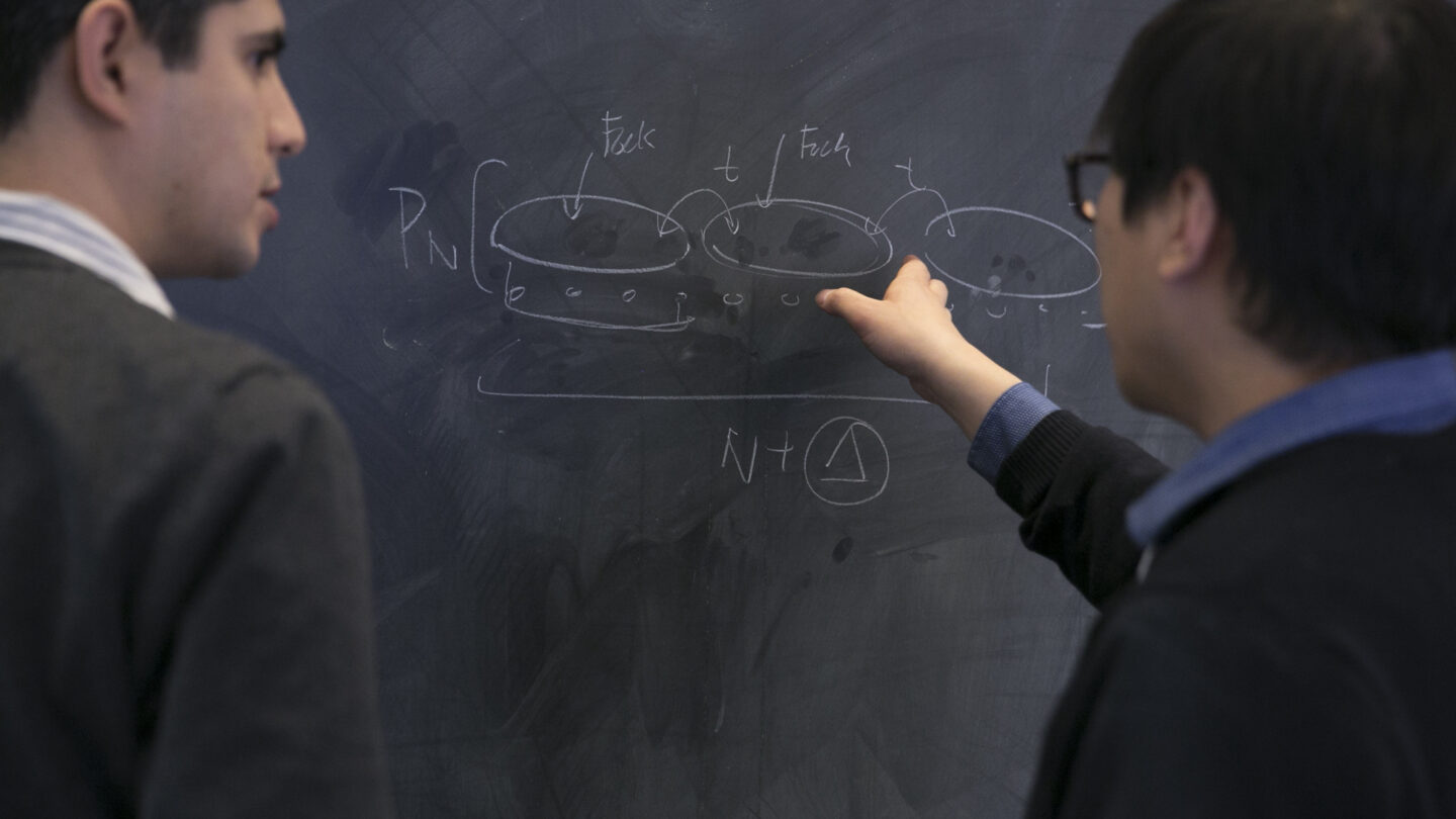 Two men looking at math on a chalkboard