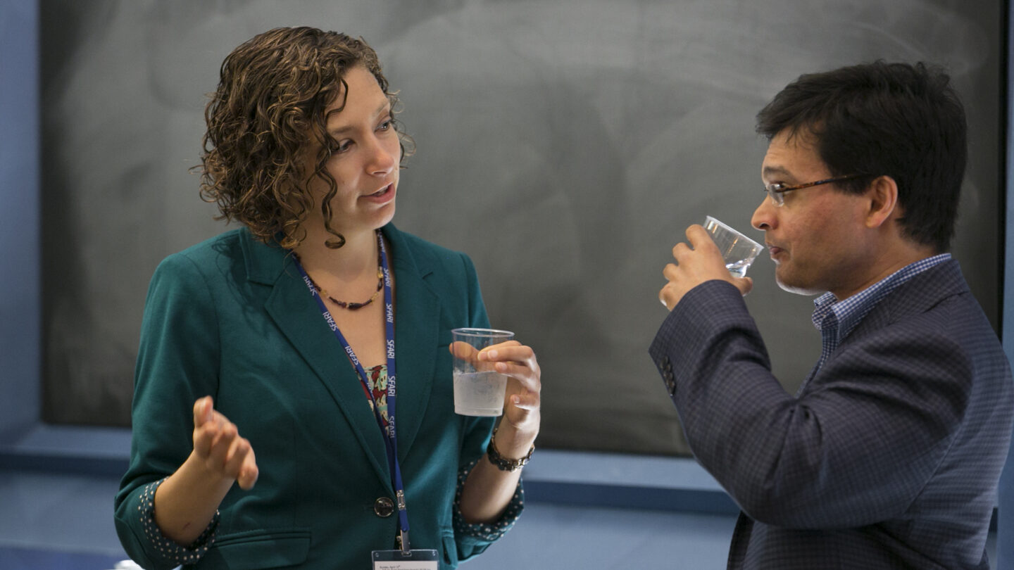 Woman and man standing and talking in front of a chalkboard