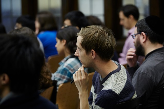People sitting in a lecture hall with hands to their chins