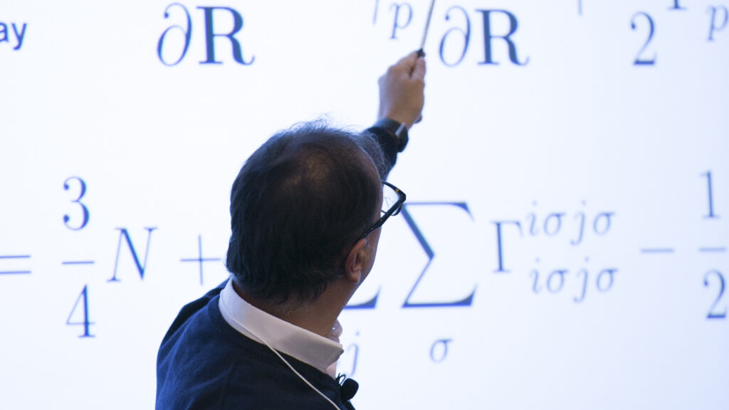 Man using a stick to point to math on a presentation