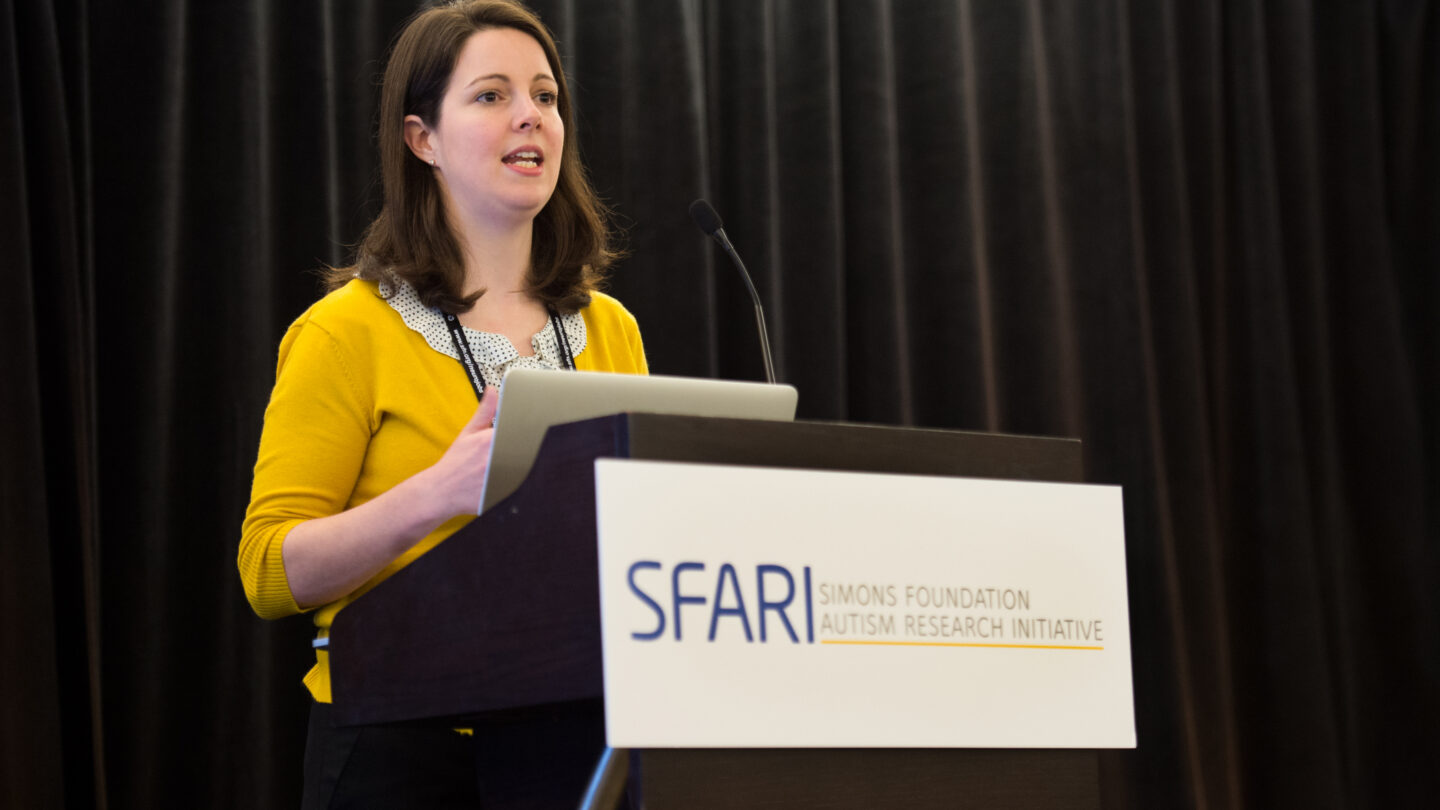 Woman standing behind a lectern that says 