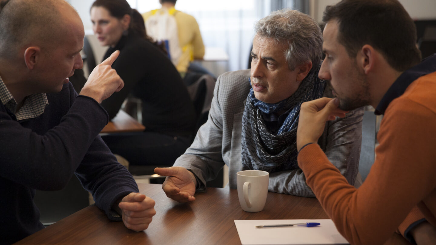 Three people sitting at a table and talking