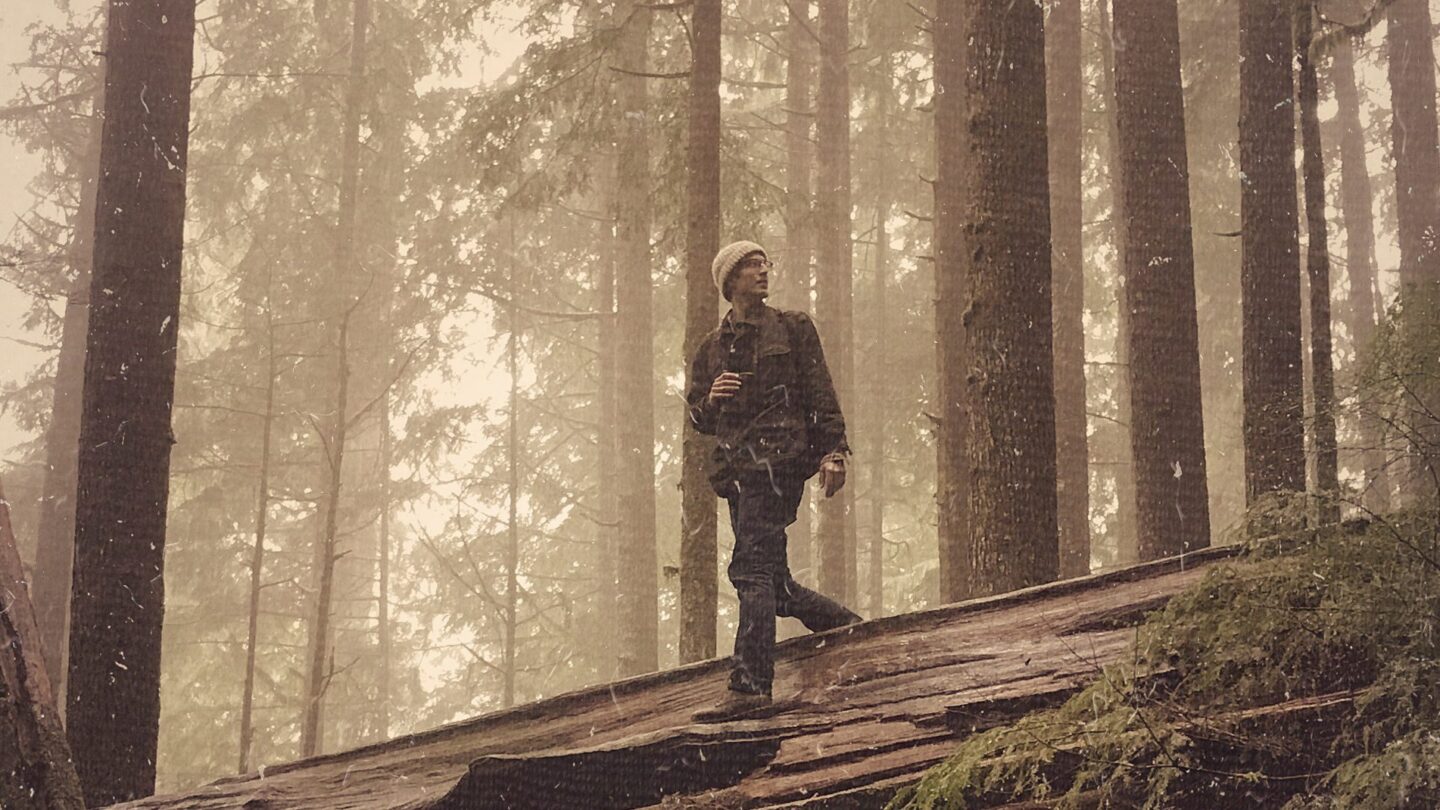 Young Bob Paine standing on a fallen tree in a forest