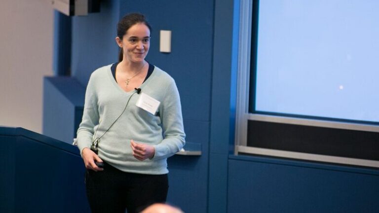 Katherine Cora Ames standing next to a lectern, presenting a slideshow
