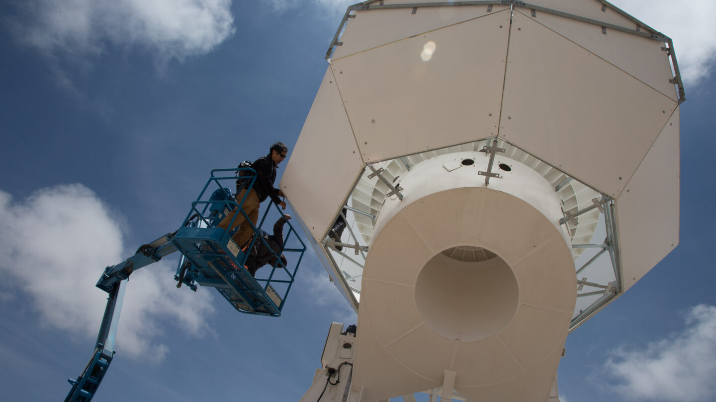 Man in a crane working on the Simons Observatory