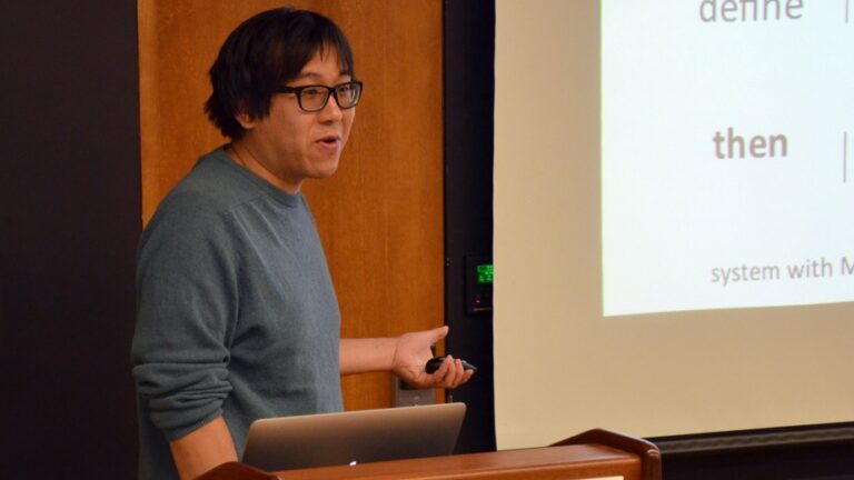 Man standing behind a lectern that says Simons Center for Geometry and Physics