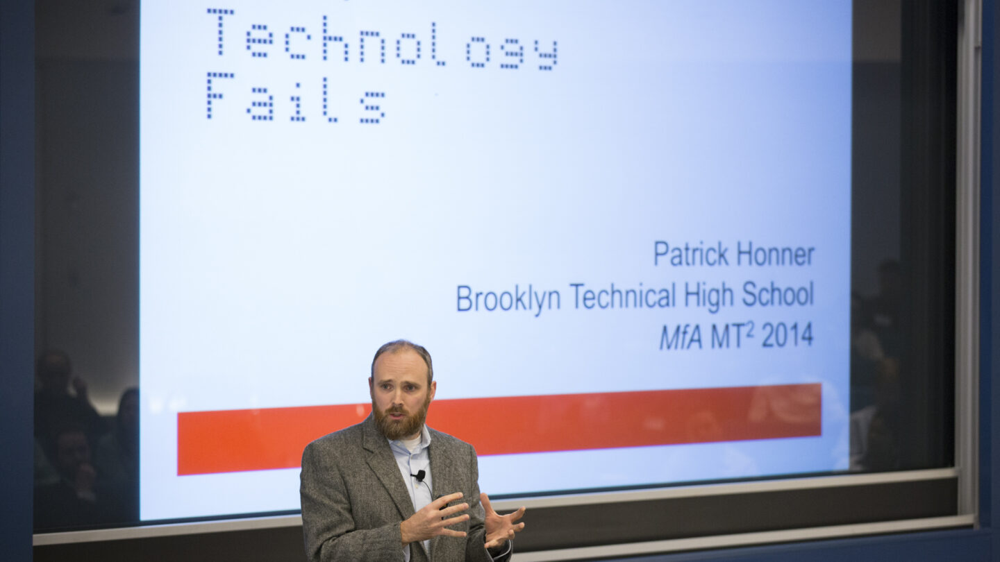 Man talking in front of a presented slideshow that says 