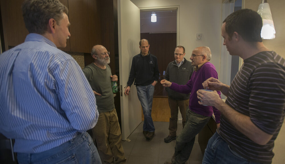 Nikolay, Kotliar, Rohringer, Gull, Georges and Ferrero standing and talking in a hallway