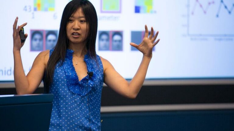 Doris Tsao presenting a slideshow as she gesticulates with both hands up
