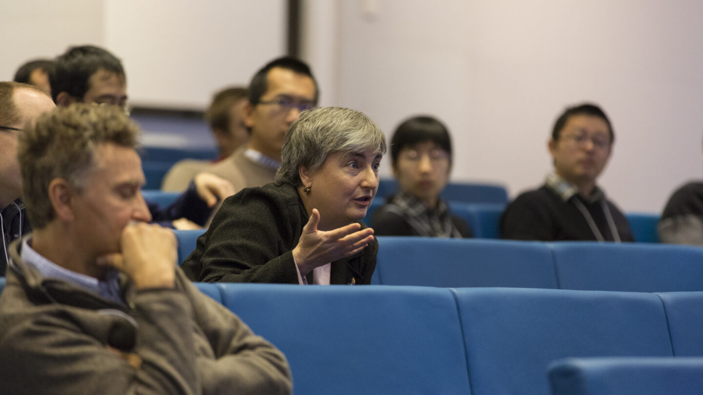 Man leaning forward in his lecture hall seat as he talks