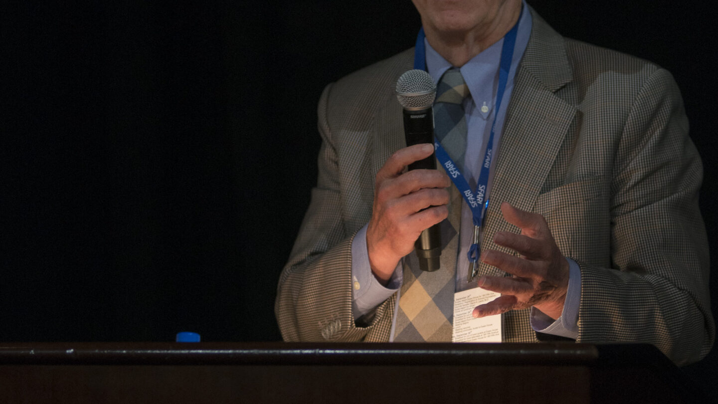 Man talking behind a lectern that says SFARISimons Foundation Autism Research Initiative