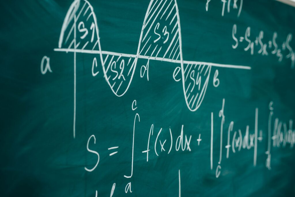 A photograph of a series of complex equations written in chalk on a chalkboard.