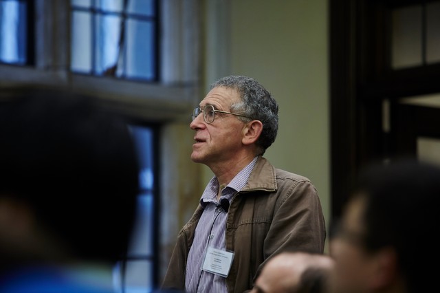 Side-shot of man standing amid a crowd of sitting people