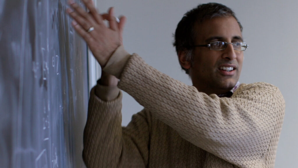 Akshay Venkatesh gesticulating to a chalkboard