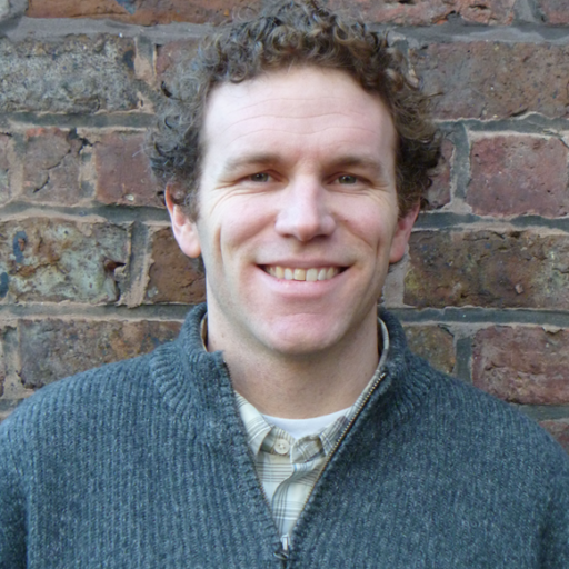 Portrait photo of Andrew Barton in front of a brick wall