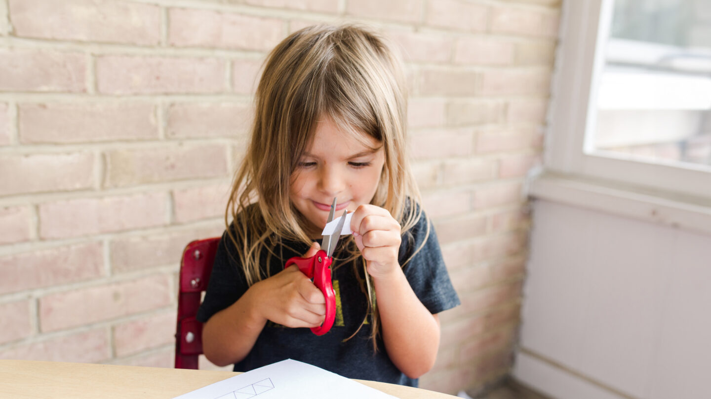 A little girl practices using scissors