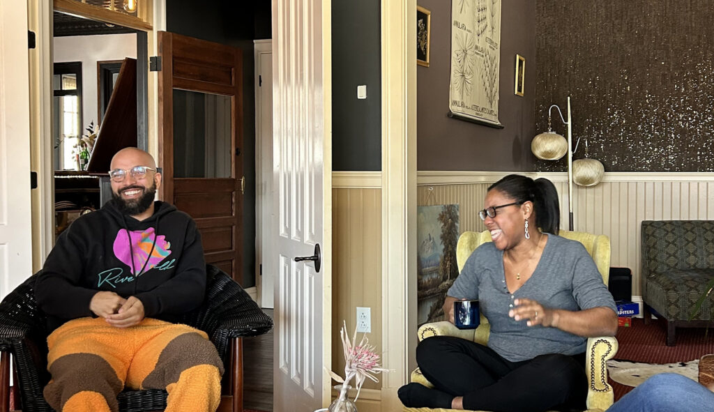 A man and a woman seated indoors, laughing.