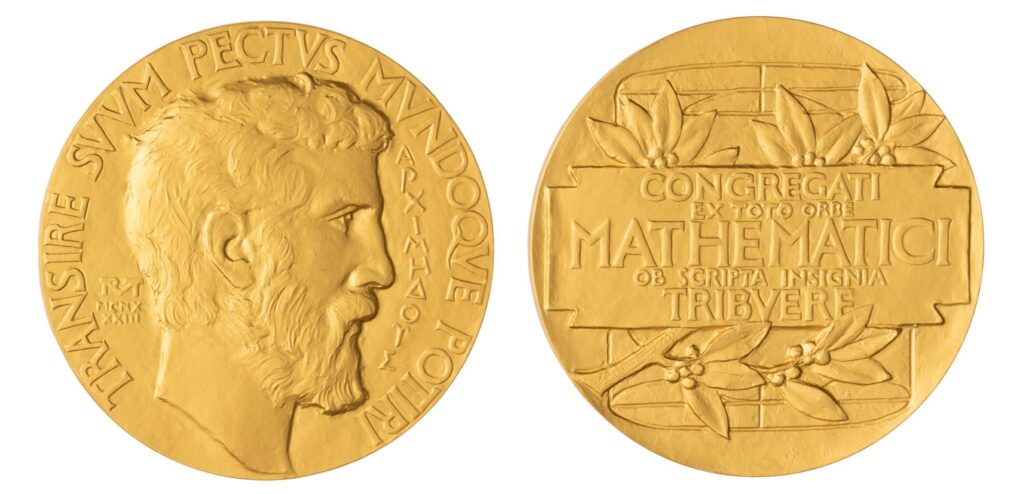 A gold Fields Medal showing a mans profile on the front and a Latin inscription with olive branches on the back.