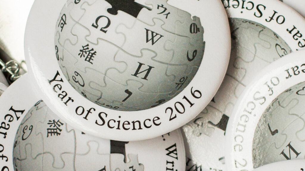 Pile of round Wikipedia Year of Science pins with the Wikipedia logo in the center and words 