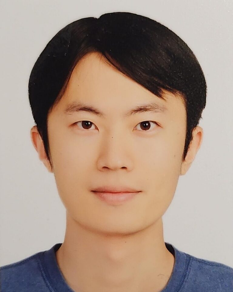 A young person with straight black hair, wearing a blue shirt, is facing the camera and smiling softly in a passport-style photo against a plain white background.