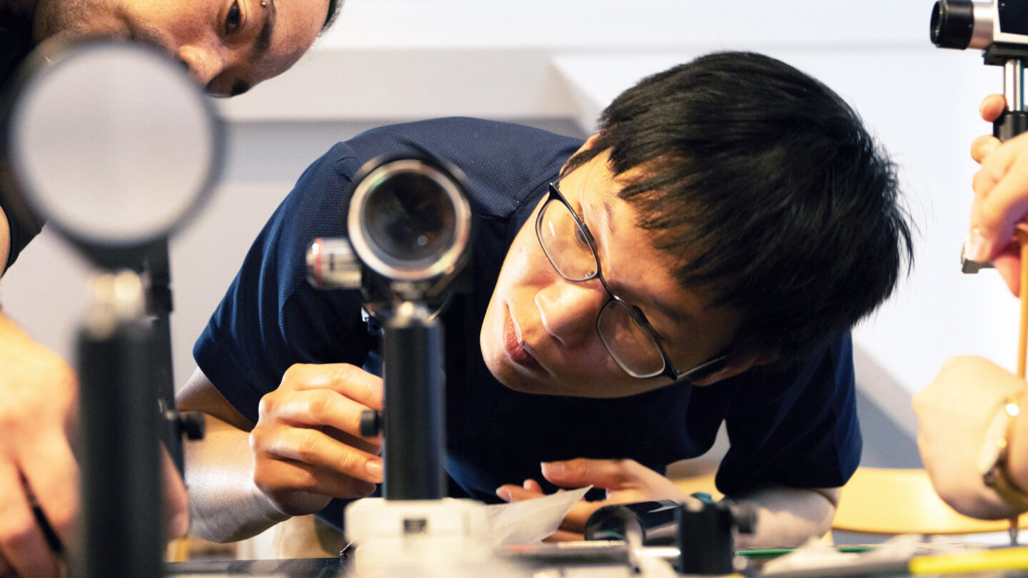 A photo of a student looking into a benchtop microscope.