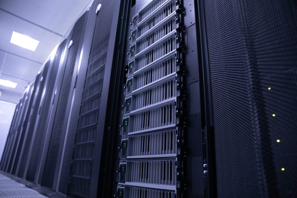 Rows of black server racks with blinking green indicator lights in a brightly lit data center. The image highlights the front view of the servers, emphasizing a clean, high-tech environment.