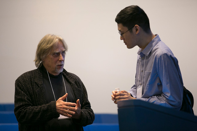 Two men talking while standing in the rows of lecture hall seats