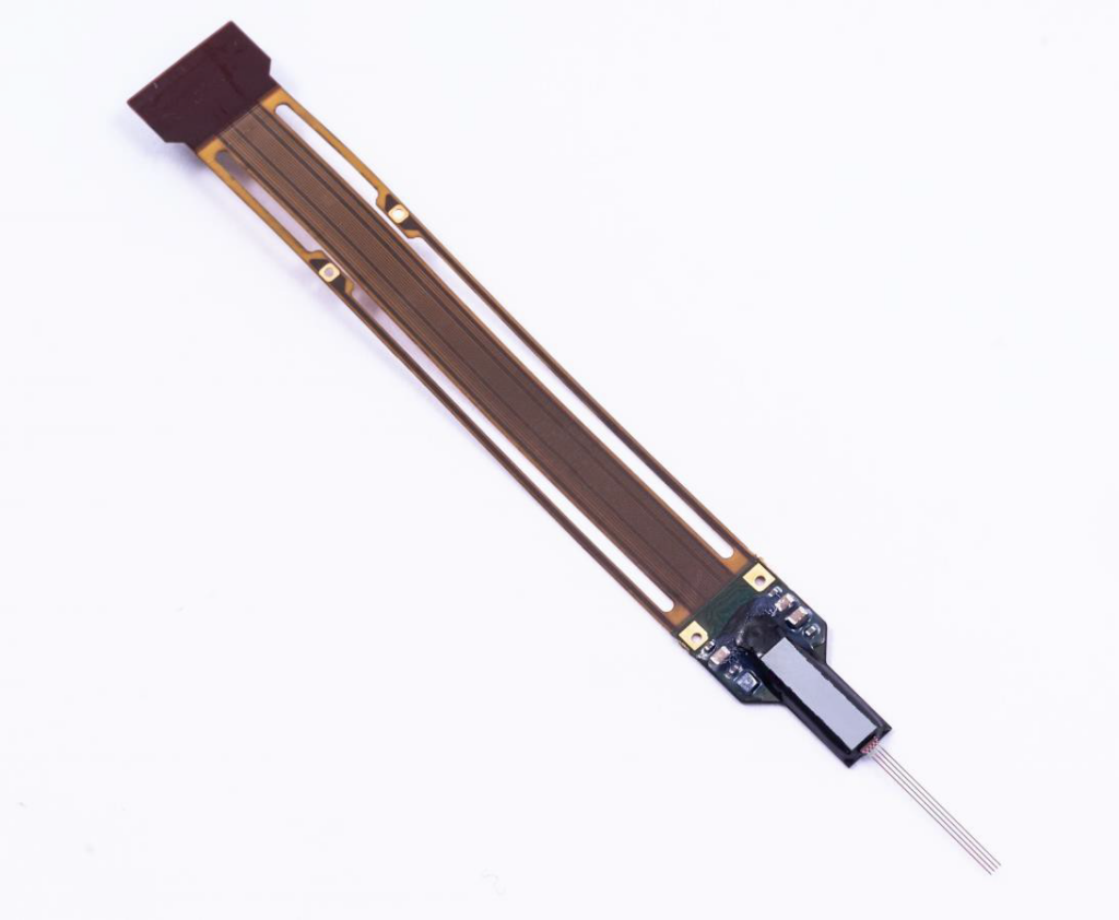 A photograph of the Neuropixels 2.0 neural recording probe, which appears as a 2-D syringe-shaped device with 4 thin needles at its very end.