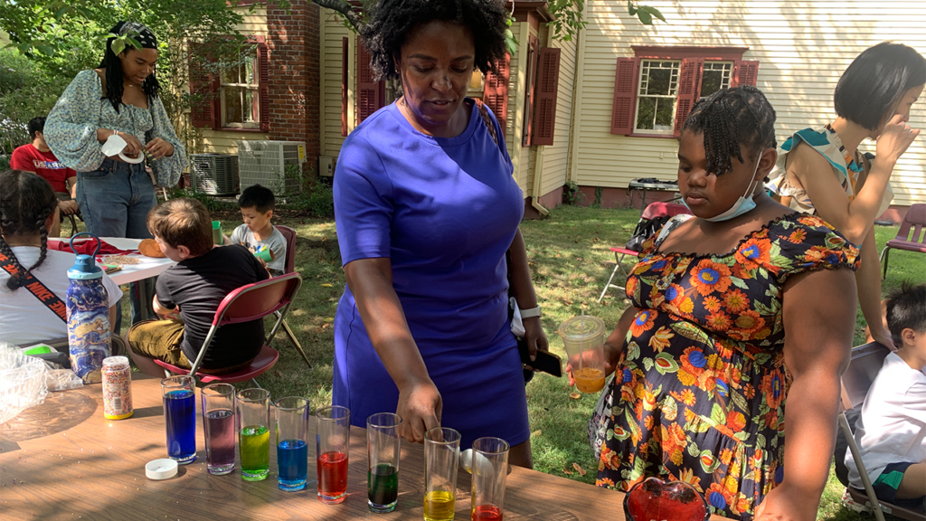 Two people standing outdoors in front of a table