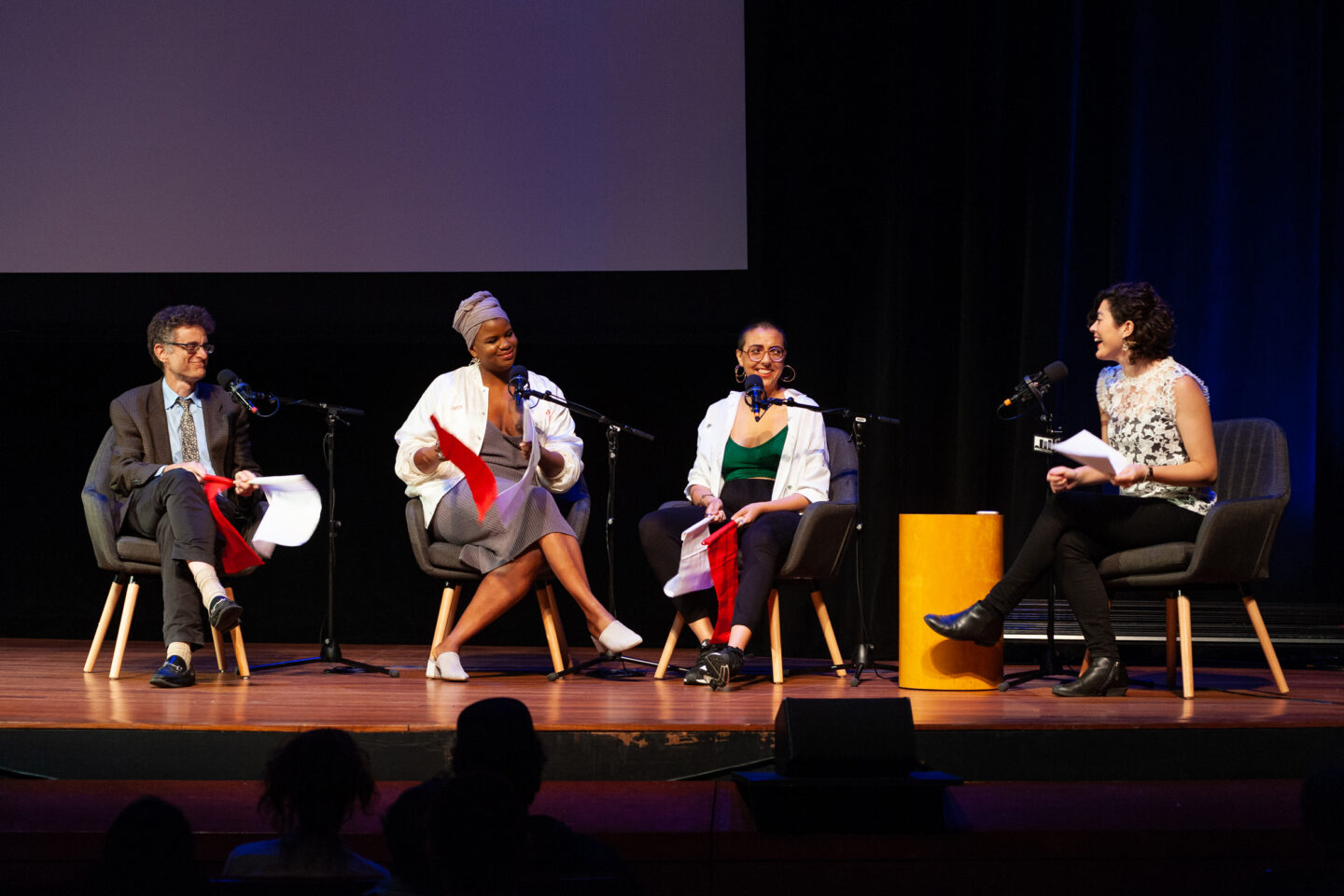 Four people sitting on individual couches on a stage
