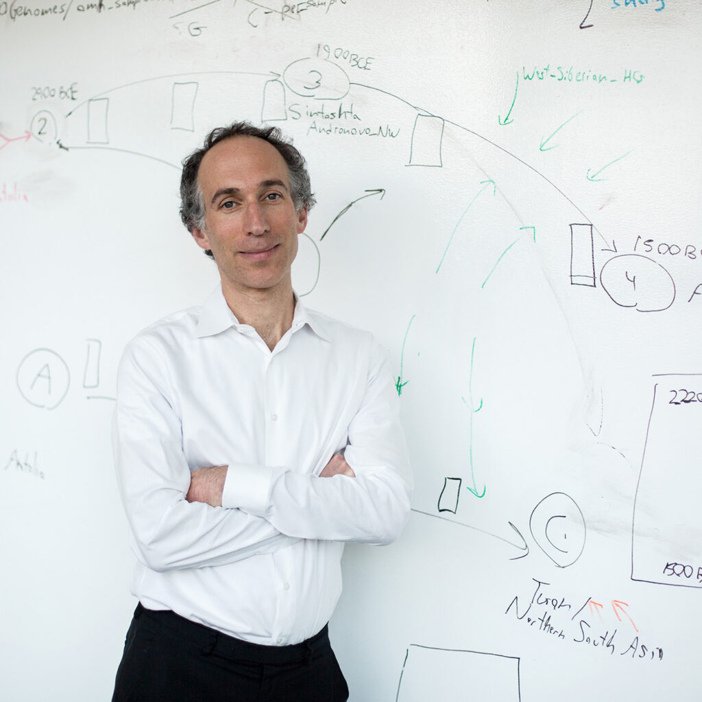 David Reich leaning on a whiteboard