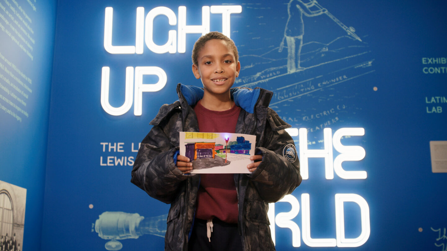 A child visitor to Lewis Latimer House holds up a lighting project completed at the museum.
