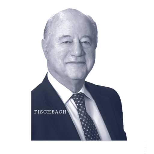 Older man in a suit and patterned tie, smiling, with the word FISCHBACH in capital letters to the left. The background is plain white.