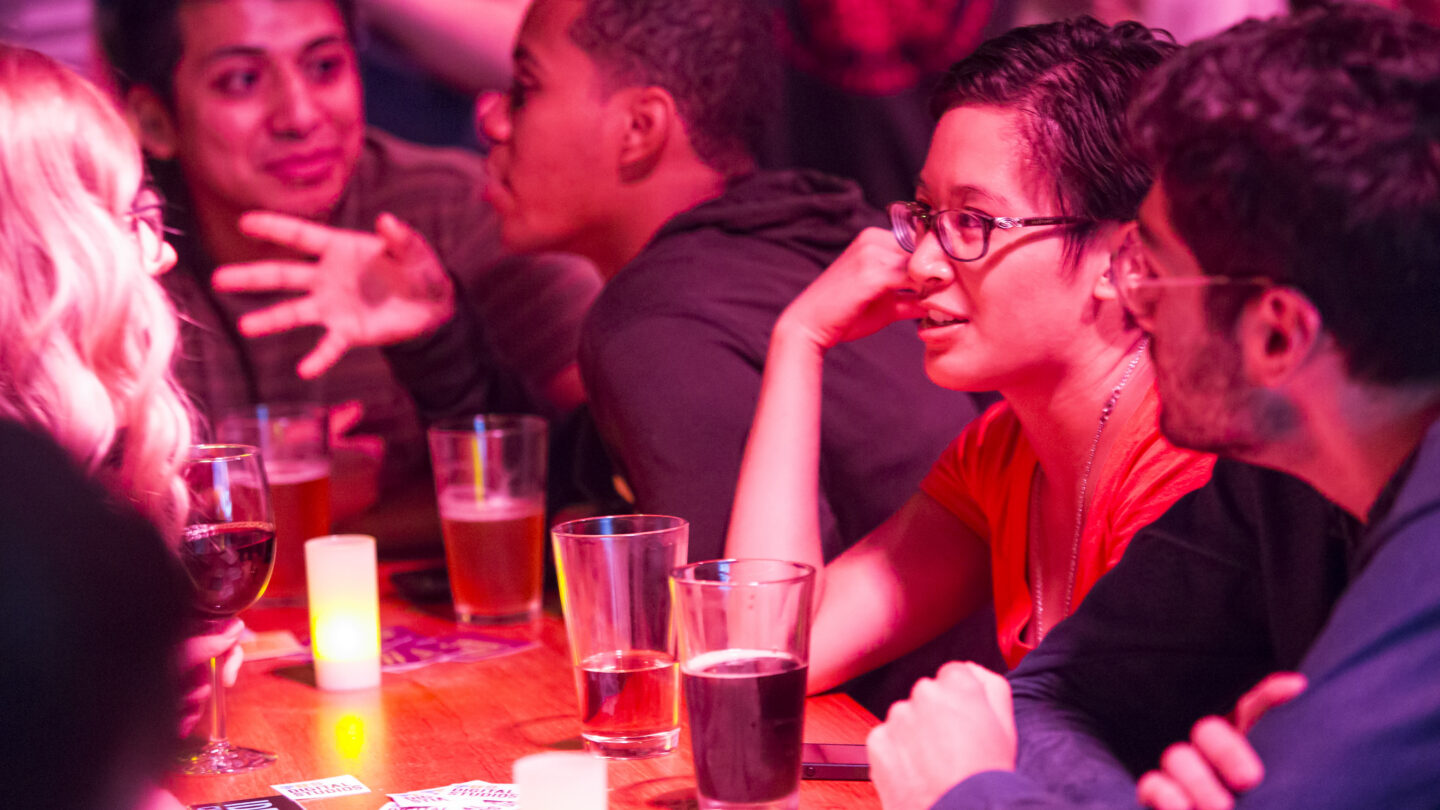 People talk at bench tables over drinks