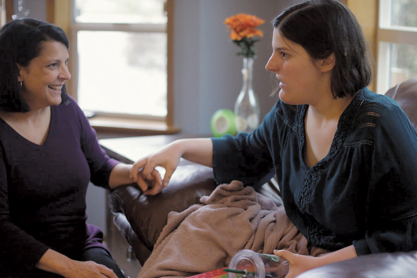 Two sitting women touching hands