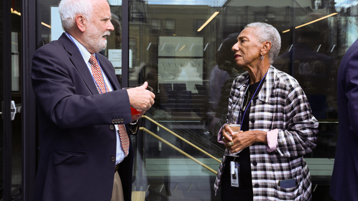 A photograph of one man and one woman talking in an outdoor space.