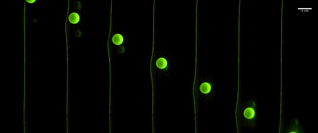 A ball falling through goopy liquid will generate a wave in a nearby flexible rubber sheet