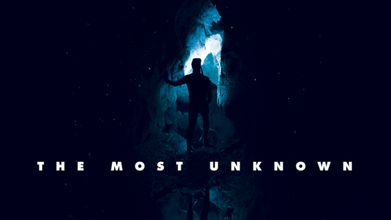 A person stands in a dark cave entrance with blue light shining in, surrounded by darkness. Text at the bottom reads THE MOST UNKNOWN..