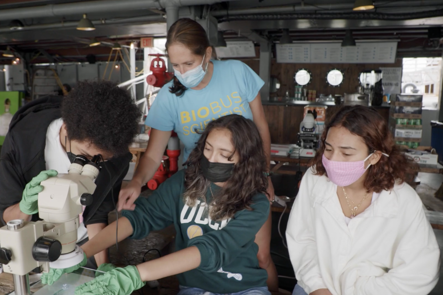 3 Students and a teacher working with microscope