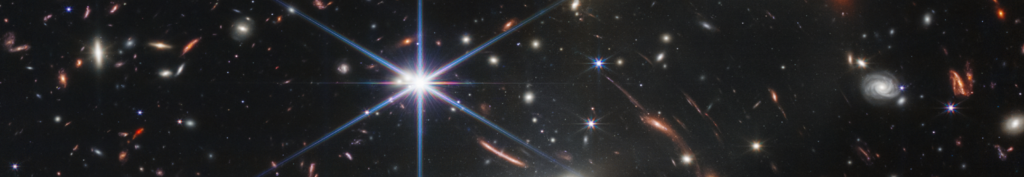 A dense star field in deep space with a large, bright star at the center, surrounded by galaxies, distant stars, and glowing cosmic dust against a dark background.
